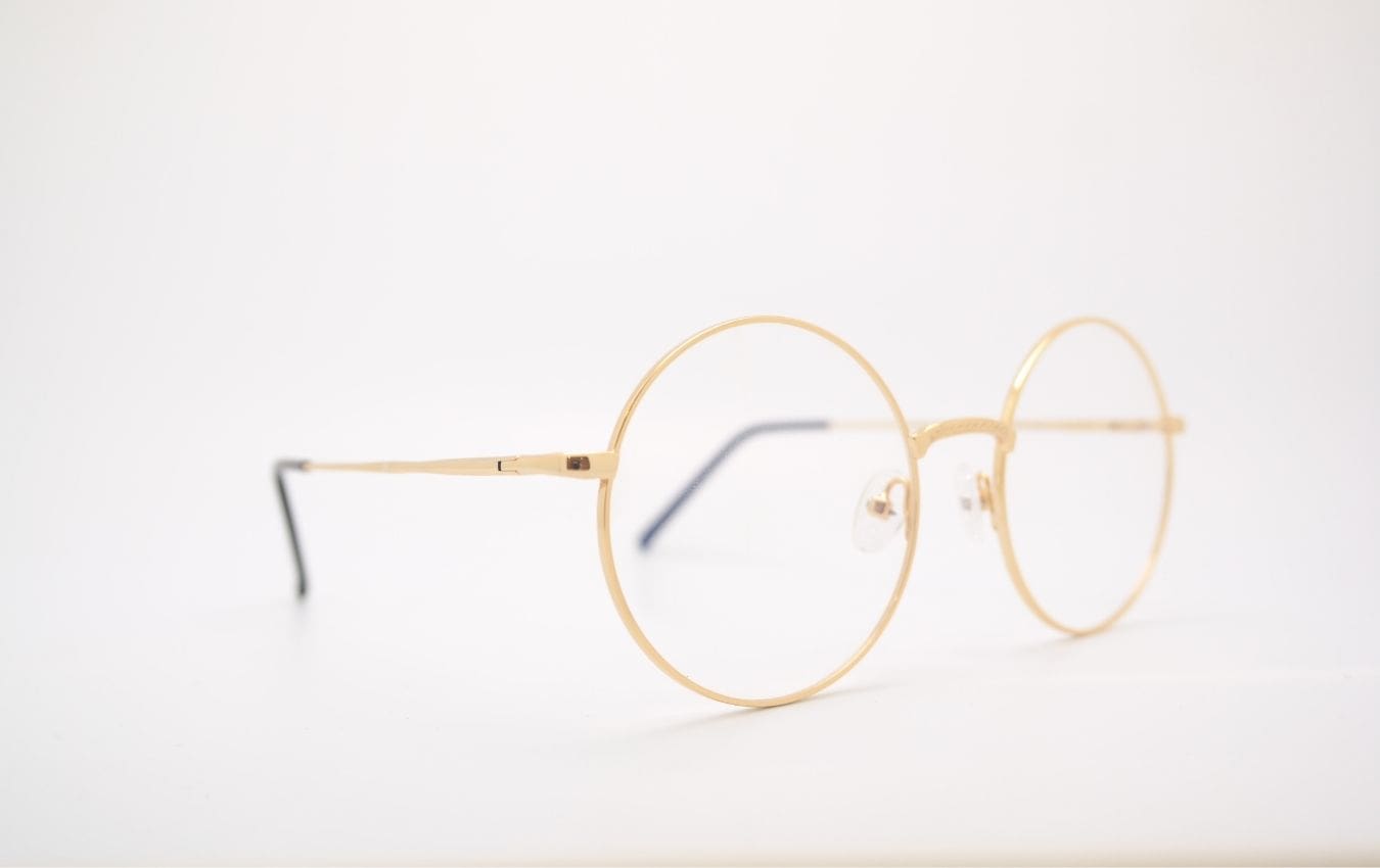lunettes rondes avec une monture dorée, fond blanc minimaliste