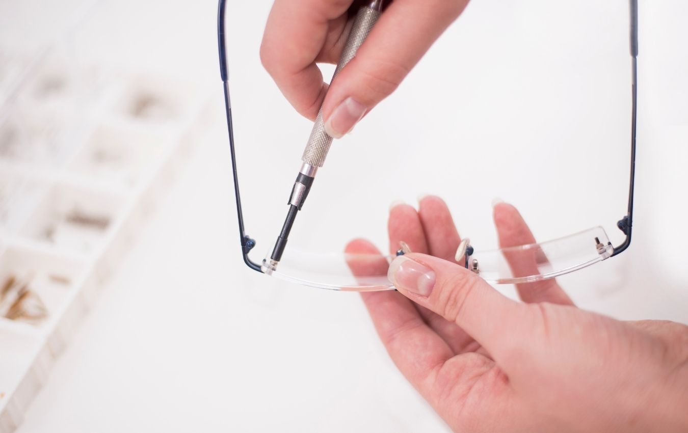 réparation minutieuse de la monture d'une lunette, mains en train de réparer